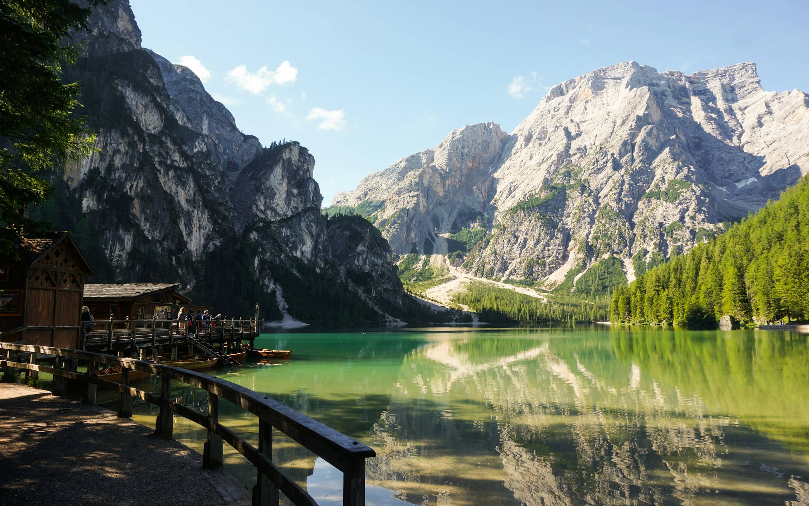 The boathouse and jetty at Lago di Braies, still green water reflecting the Dolomite wall behind.